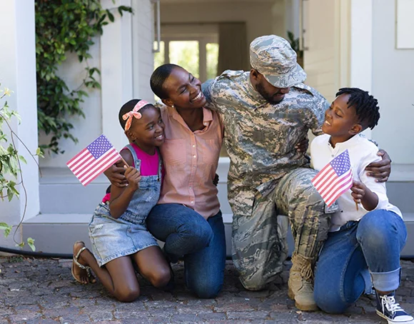 Active-duty soldier and children celebrating home purchase with American flags – veteran-friendly real estate services in Temple, TX